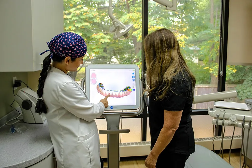 Dentist showing a patient a dental model on a monitor.