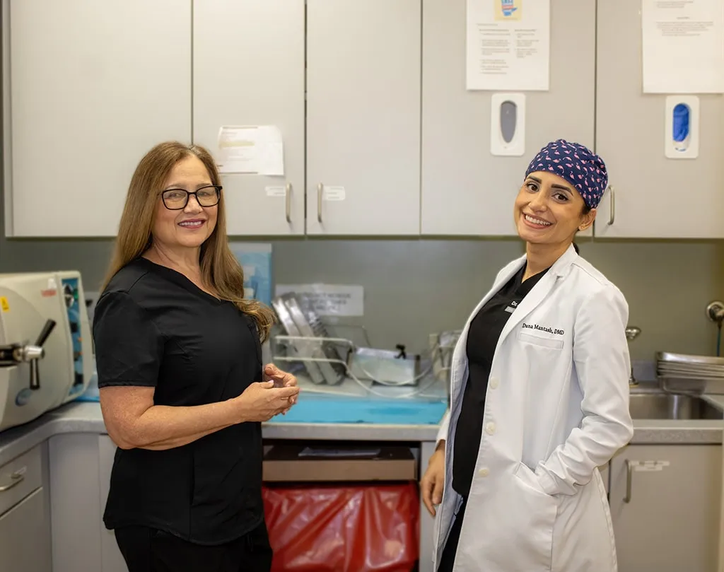 Staff member and dentist standing next to computer with dental imaging.