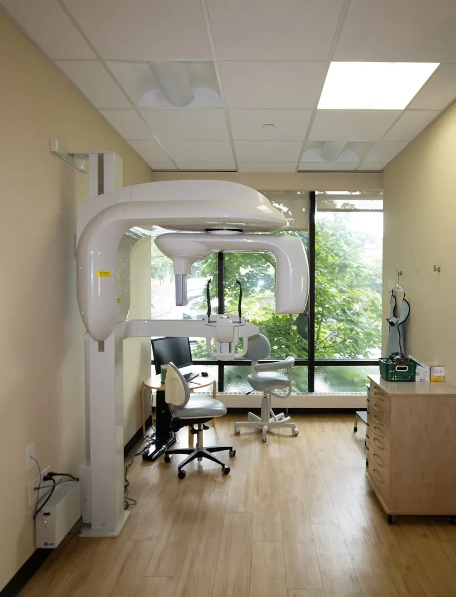 Dental operatory room with panoramic X-ray machine and large window.
