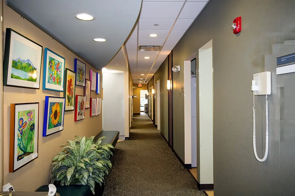 Clinic hallway with curved ceiling lights and framed artwork.