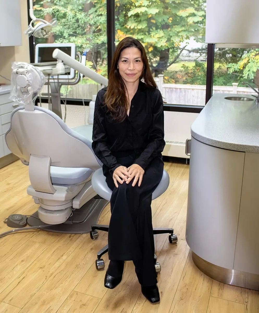 Dentist sitting in a chair in a dental procedure space with a dental chair