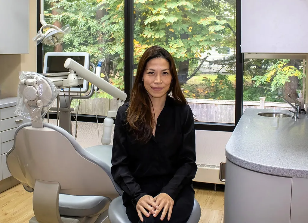 Dentist standing next to a dental cart while a patient sits in the chair.